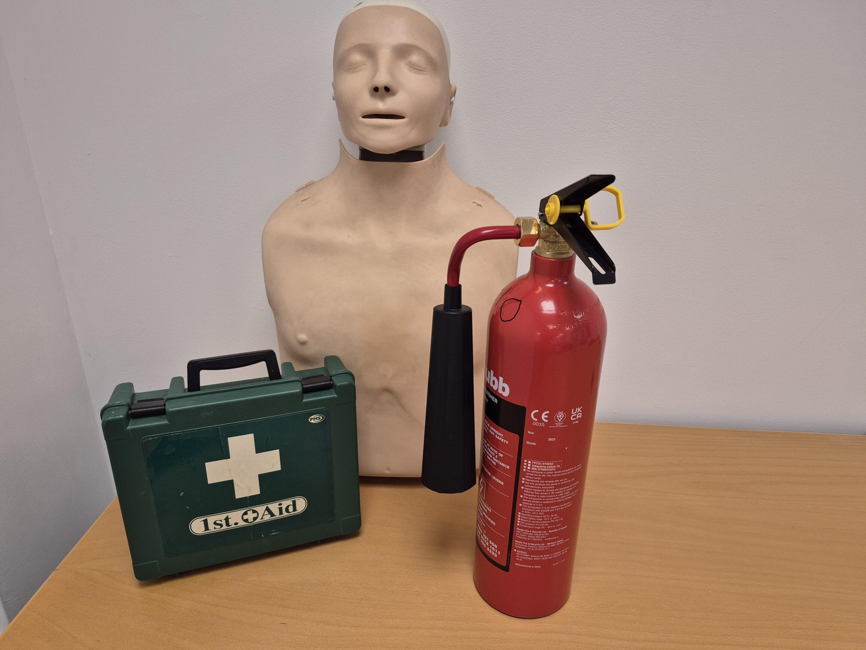 efawfm A first aid box, fire extinguisher and CPR mannikin on a desk